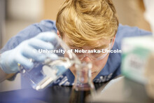 Chem 113 lab. A student pours liquids from one beaker to another in a Chemistry Lab in Hamilton Hall