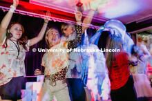 Students dancing in a "Rave"-like setting with glow lights and beach balls bouncing through the crow