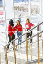 Cather Dining Center photoshoot. Young women talking in front of the large windows in the Cather Din
