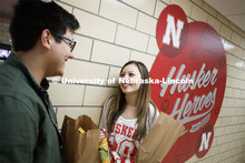 Selleck Dining Center photo shoot. Students standing next to the Husker Heroes logo in Selleck Dinin