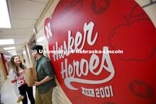 Selleck Dining Center photo shoot. Students standing next to the Husker Heroes logo in Selleck Dinin