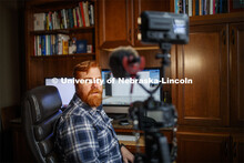 Tyler White records a lecture in his home office while his son, Gavin, 7, plays with their dog Riple