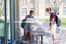Jordyn Preston spreads out a tablecloth on the tables outside the Adele Coryell Hall Learning Common