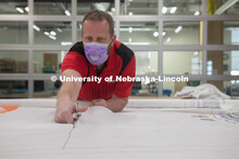 Jerry Reif, shop manager at Nebraska Innovation Studio, cuts hospital gowns from Tyvec material hous