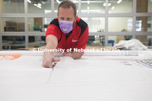 Jerry Reif, shop manager at Nebraska Innovation Studio, cuts hospital gowns from Tyvec material hous