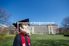 Herbie Husker stands on the lawn in front of Love Library and is decked out in graduation attire for
