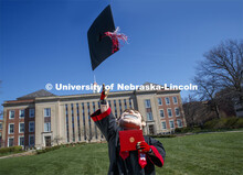 Herbie Husker removes his mortarboard and tosses it in the air in front of Love Library and is decke