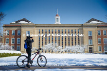 A young man riding by stops to take a picture of Love Library. An April snowstorm leaves campus unse
