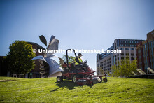 Tyler Kingsley, a worker with FM&P Landscape Services, mows outside the Visitors Center on 12th and 