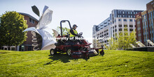 Tyler Kingsley, a worker with FM&P Landscape Services, mows outside the Visitors Center on 12th and 