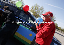 Ratch O'Connell blows up a blue balloon to decorate his vehicle.  Blue, yellow and green balloons an