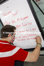 Josh Bruno, strength and conditioning coach, writes on a sign for the entrance to the weight room. F