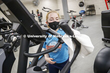 Ellenor Sell disinfects the elliptical after working out on the first day of Campus Recreation re-op