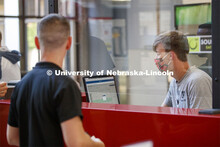 Mickey Wilson works behind a protective shield at the reception desk. First day of Campus Recreation