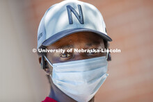 Mark Iradukunda sports a Husker baseball cap while wearing a mask. Photo shoot of students wearing m