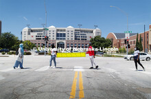 Students at the crosswalk wearing masks with Memorial Stadium in the background. Photo shoot of stud