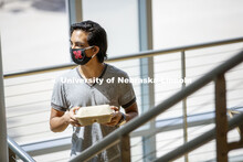 A young man wearing a Husker mask gets takeout dining from the Willa Cather Dining Center. Photo sho