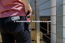 A student has their cell phone in back pants pocket and their Husker mask. Photo shoot of students w