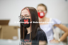 A young woman’s Husker mask matches the red stripes in her hair. Photo shoot of students wearing m