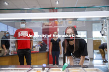 A young woman leans in toward the food bar to select her lunch at the Willa Cather Dining Center. Ph