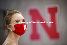 Young woman wearing a red mask stands next to the Nebraska N. Photo shoot of students wearing masks 
