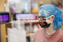 A young woman checking out in the convenience store. Photo shoot of students wearing masks and pract