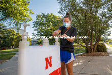 Maggie Ferguson, a May 2020 College of Business graduate, tries out a hand sanitizer station outside