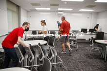 Extra chairs are moved out from a classroom in Louise Pound Hall. Crews are arking classroom seats i