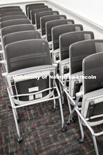 Extra chairs are moved out from a classroom in Louise Pound Hall. Crews are arking classroom seats i