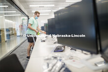 Student worker Alex Cathcart places a seat-available sticker marking in the computer lab of the John