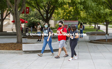 Photo shoot of students on city campus display mask wearing. Students wear masks while crossing camp