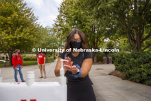 Photo shoot of students on city campus practicing hand sanitizing. A young woman stops at a hand san