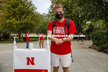 Photo shoot of students on city campus practicing hand sanitizing. A young man stops at a sanitizing