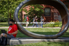 Photo shoot of students on city campus display mask wearing and social distancing. A young man sits 
