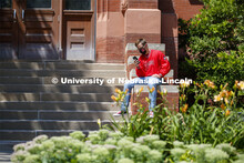 Photo shoot of students on city campus display mask wearing. A masked young man sits outside Richard