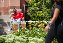 Photo shoot of students on city campus display mask wearing. A masked young man sits outside Richard