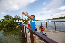 Malayna Wingert, a sophomore from Sterling, NE, lifts a water sample out of Holmes Lake as Anni Poet