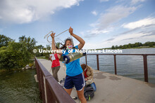 Malayna Wingert, a sophomore from Sterling, NE, lifts a water sample out of Holmes Lake as Anni Poet