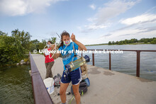 Malayna Wingert, a sophomore from Sterling, NE, lifts a water sample out of Holmes Lake as Anni Poet