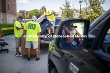 The Student Move-In Team unloads a truck. A student masks up while waiting for his turn to unload at