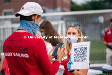 A Nebraska Campus Recreation employee (right) holds up a QR code for students to scan during the Hus