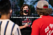 A member of the Nebraska Rugby Club (center) speaks to students during the HuskerMania Masker Singer