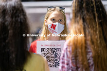 An employee of Nebraska Campus Recreation (center) speaks to students and holds up a QR code for the