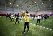 Horns up, covered and masked is all part of the Cornhusker Marching Band practice in Cook Pavilion. 
