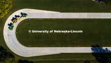 A tractor pulls the test car (yellow) and an additional tractor for weight as it rounds the test tra