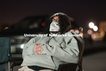 Bundled against the cool evening, James Le Sueur watches his film from a lawn chair near the screen.