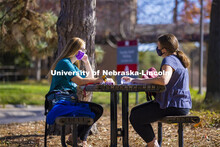 Madyson Hamling (dark blue top) and Emma Arthur study outside the Barkley Memorial Center on a warm 