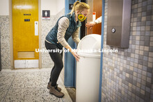 Anna Oetting, graduate students working in the Office of Sustainability, loads an old trashcan onto 