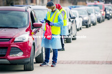 Sam Newell hands a drive-up testing participant their sample at the East Stadium loop saliva testing