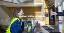 Wellness attendant Katie Lockyear checks the status card as people enter Hawks Hall. Students met th